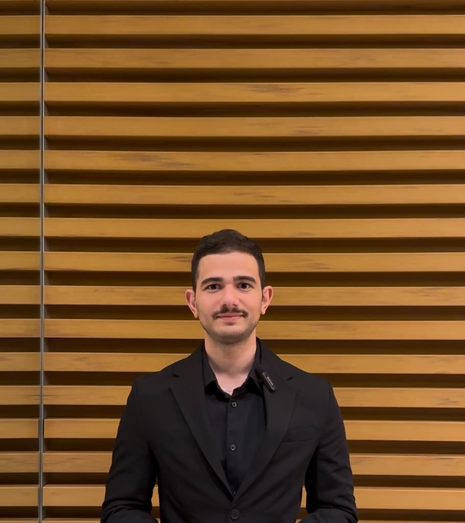 Portrait of Yazan Alamin, automation and AI engineer at Ordron, in professional attire against a timber slat wall.